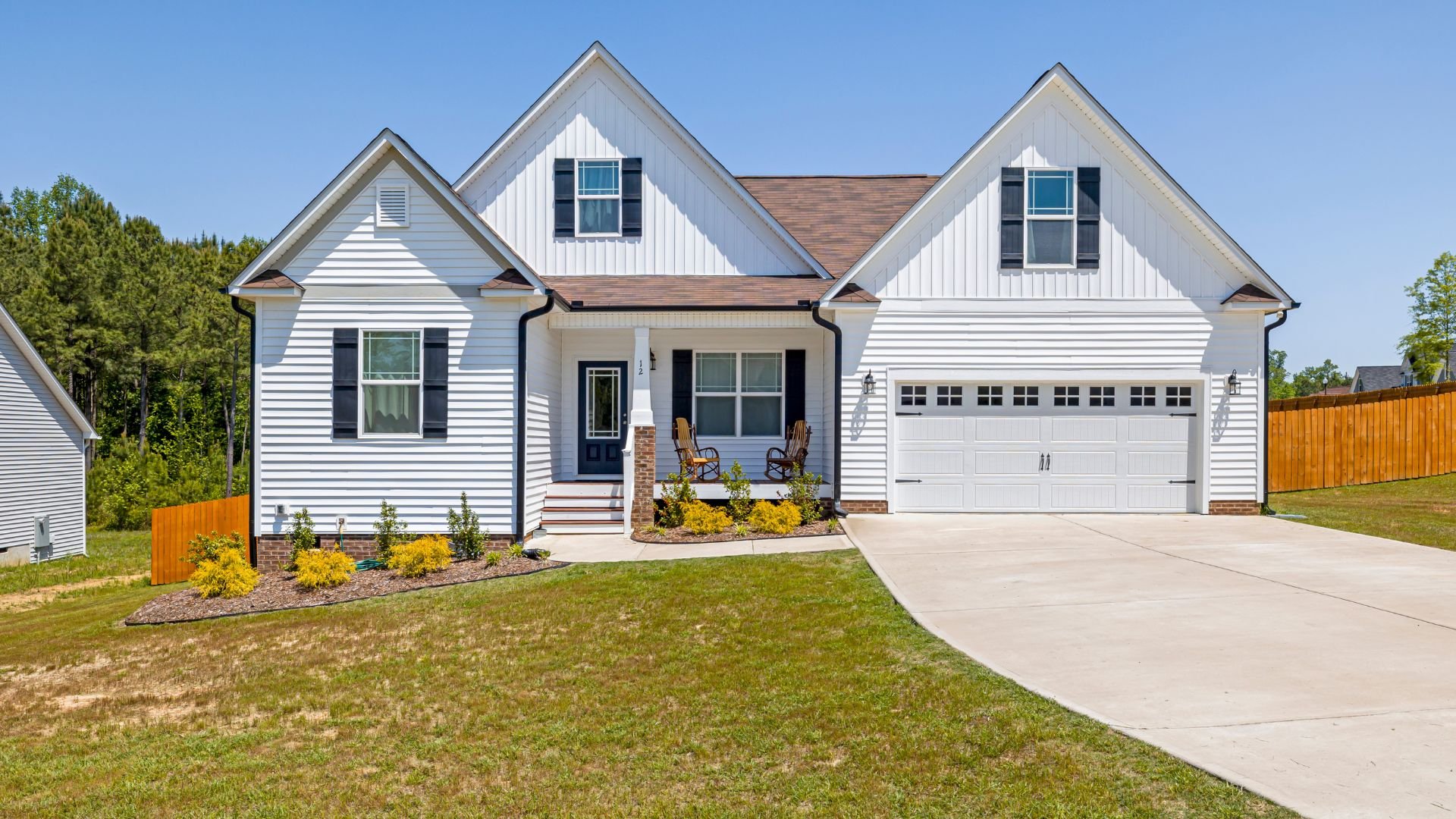 White suburban house with two-car garage and yellow flower landscaping