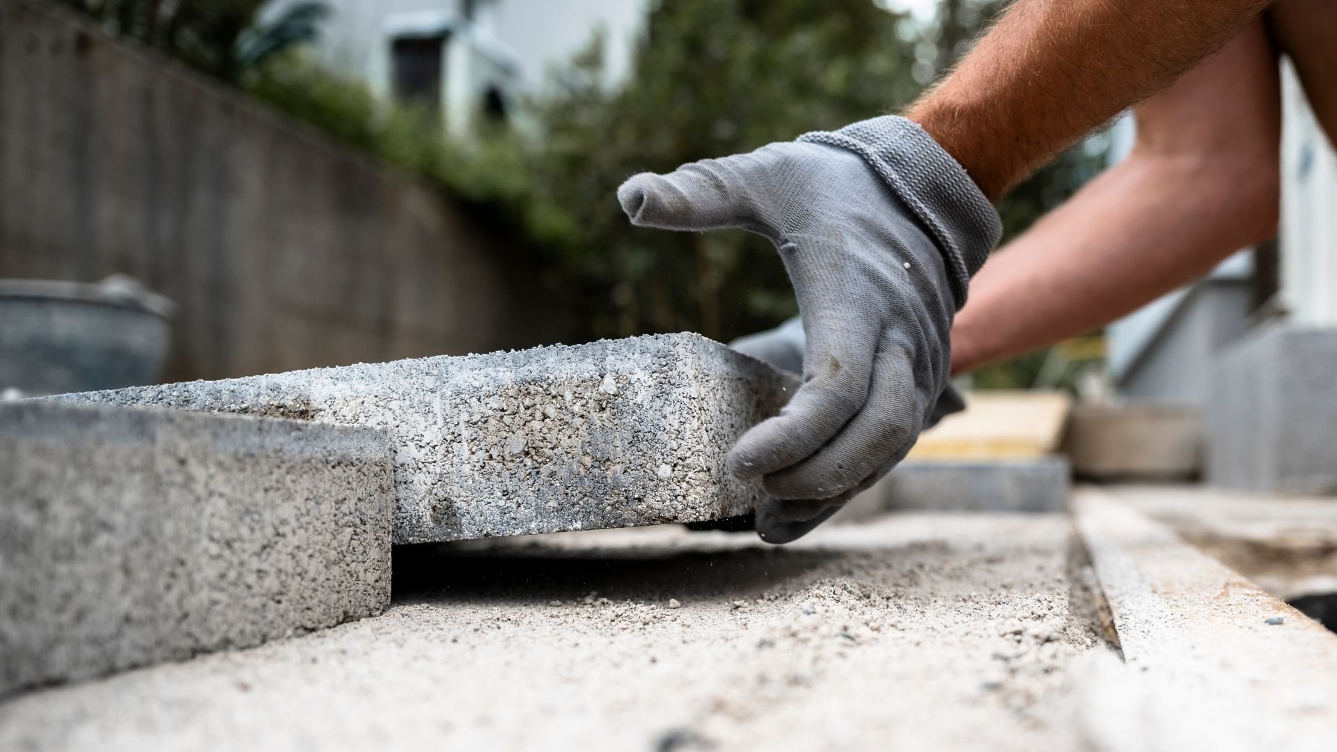 Worker placing concrete paving stone during outdoor landscaping project