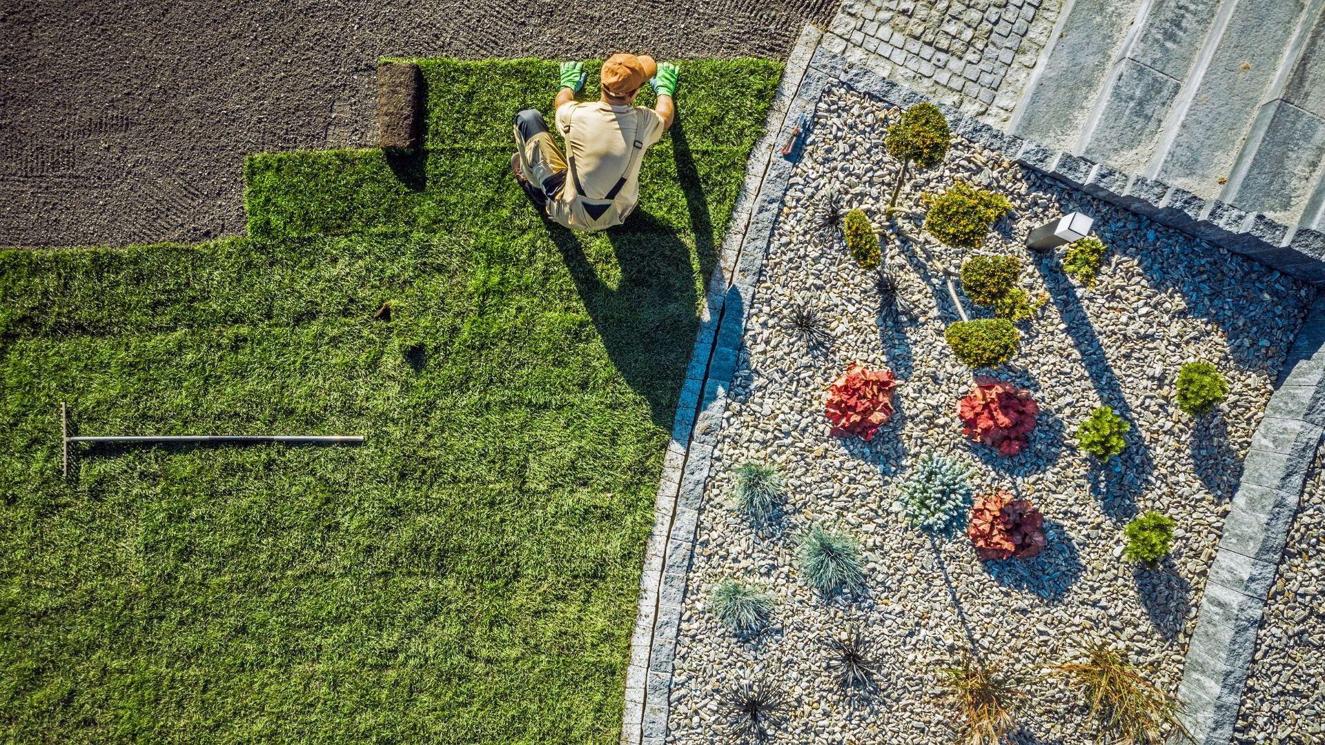 Aerial view of landscaper working on green lawn and stone garden